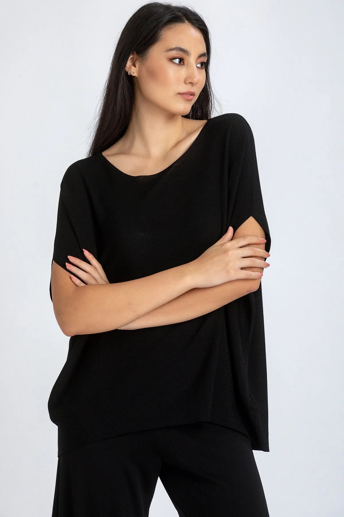 Modella indossa maglia premaman nera a maniche corte dal taglio morbido, sfondo chiaro.