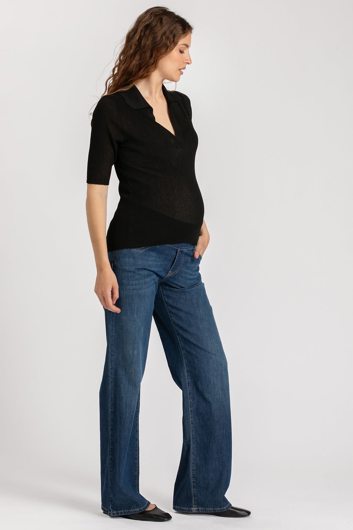 Donna incinta con maglia nera premaman e jeans, abbigliamento premaman elegante