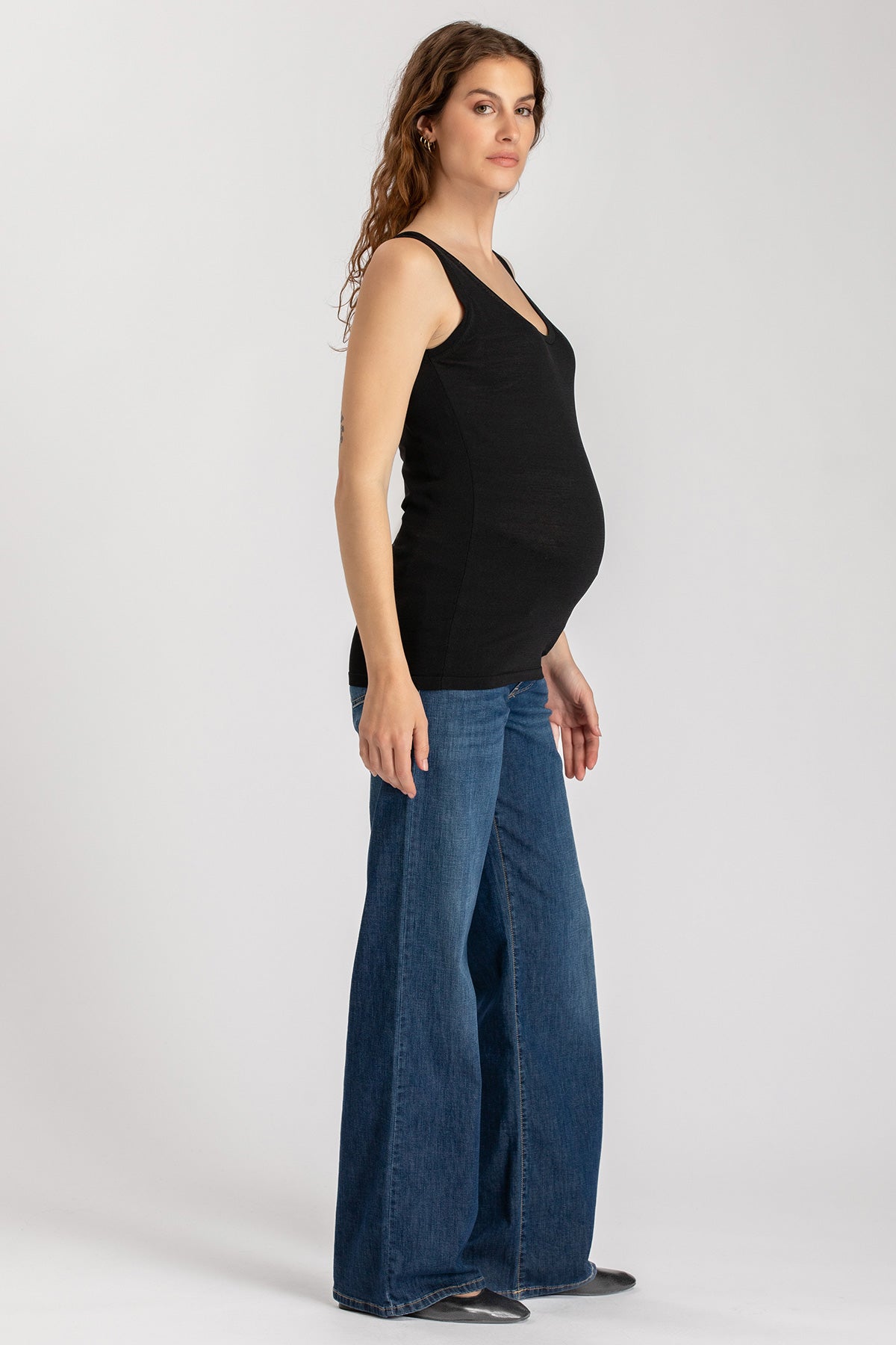 Donna incinta con top nero e jeans premaman a zampa, abbigliamento premaman elegante