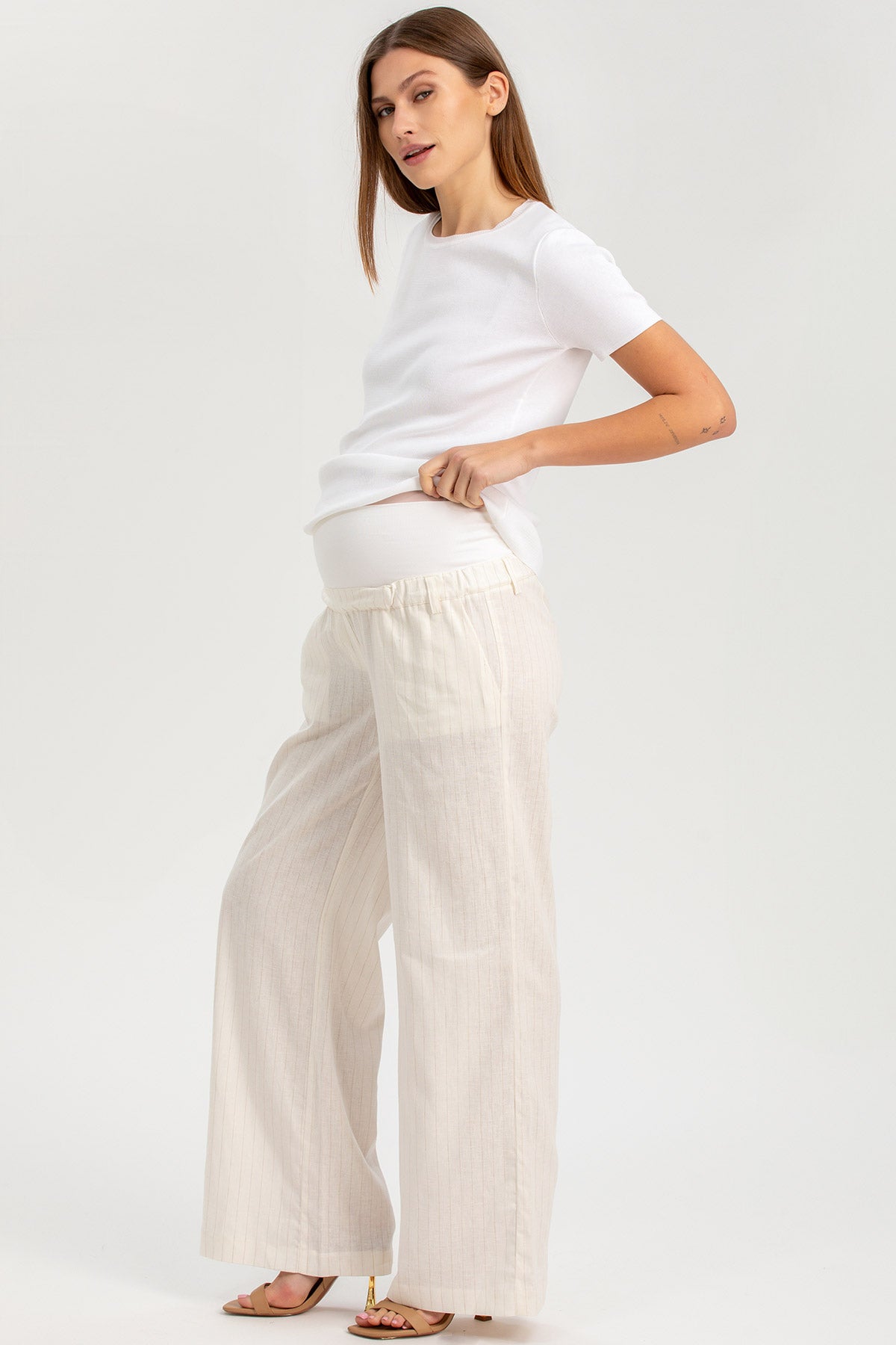 Donna incinta con pantaloni premaman larghi color panna e maglietta bianca