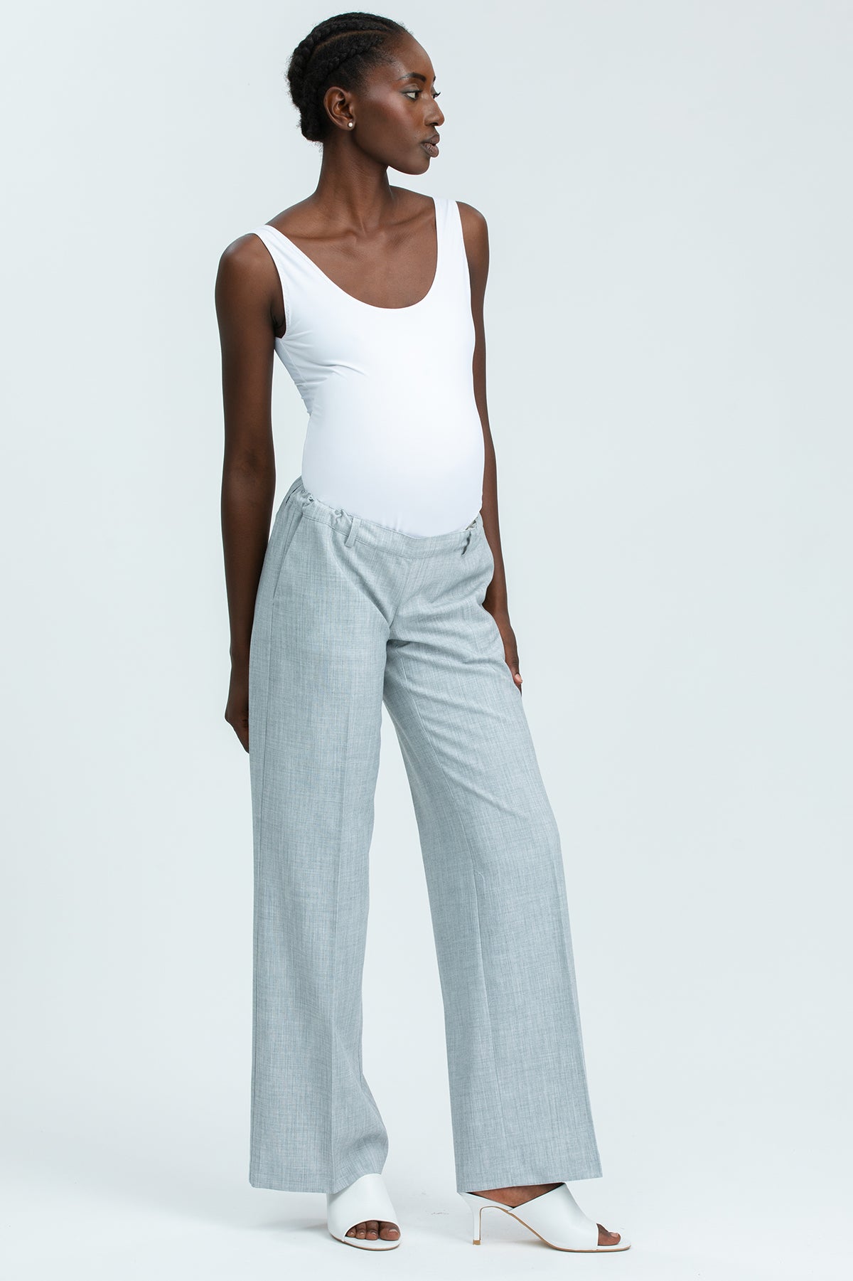 Modella indossa pantaloni premaman grigi a gamba larga e body bianco