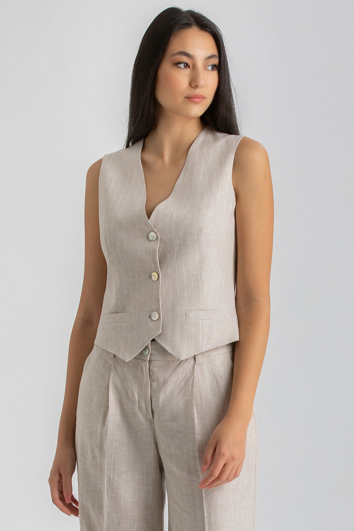 Donna con completo premaman beige senza maniche e pantaloni, abbigliamento premaman elegante