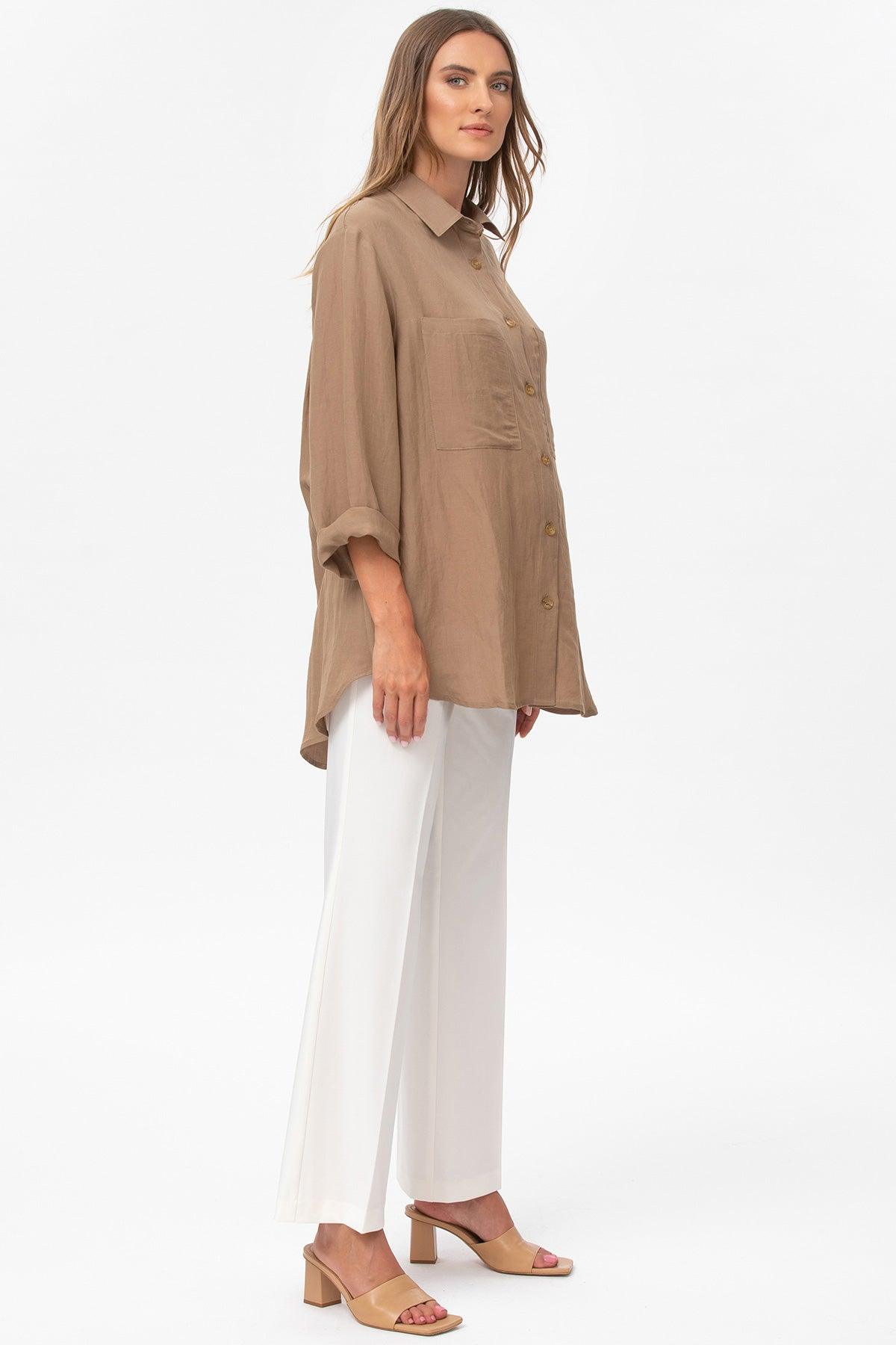 Donna indossa camicia premaman beige oversize e pantaloni bianchi eleganti