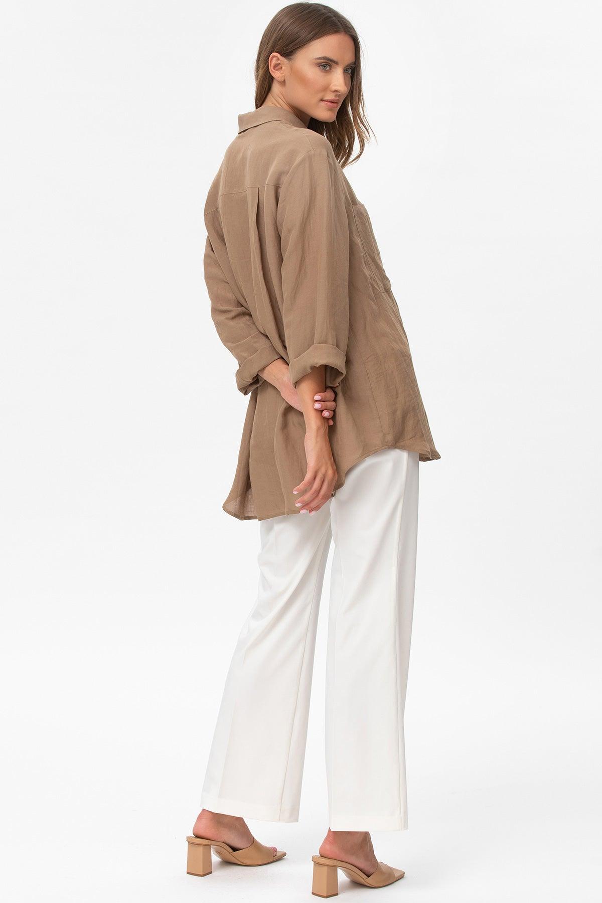 Donna con camicia lunga beige premaman abbinata a pantaloni bianchi eleganti
